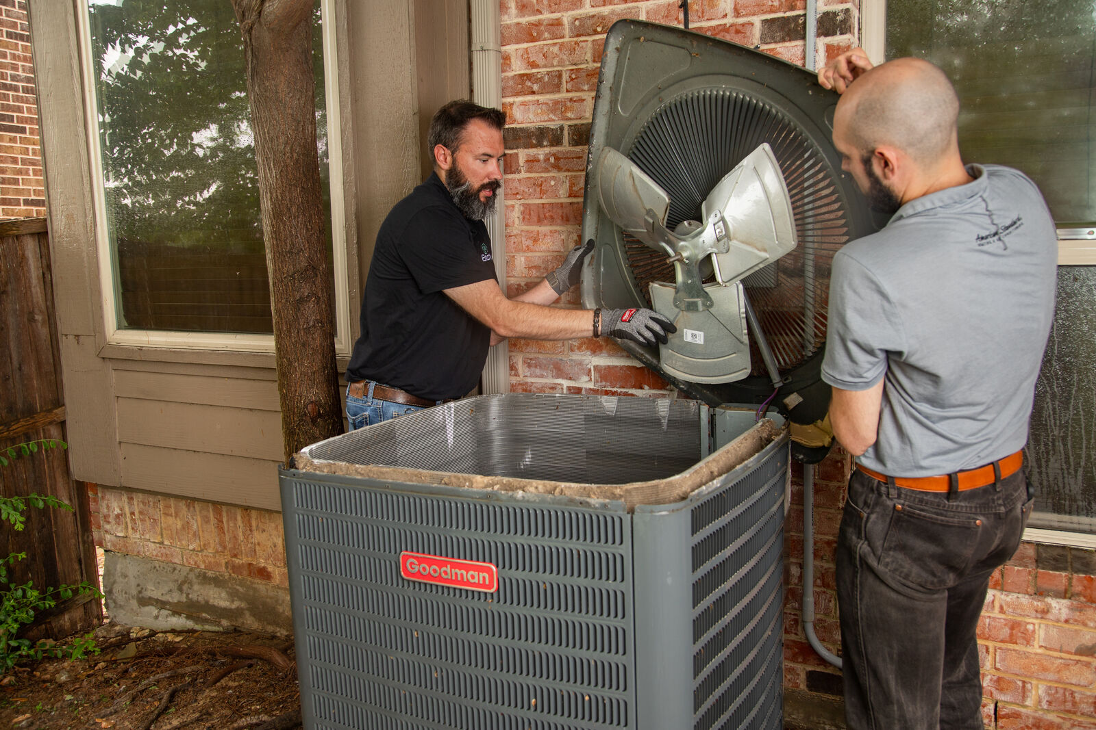 Team Enoch technicians installing an outdoor condenser unit