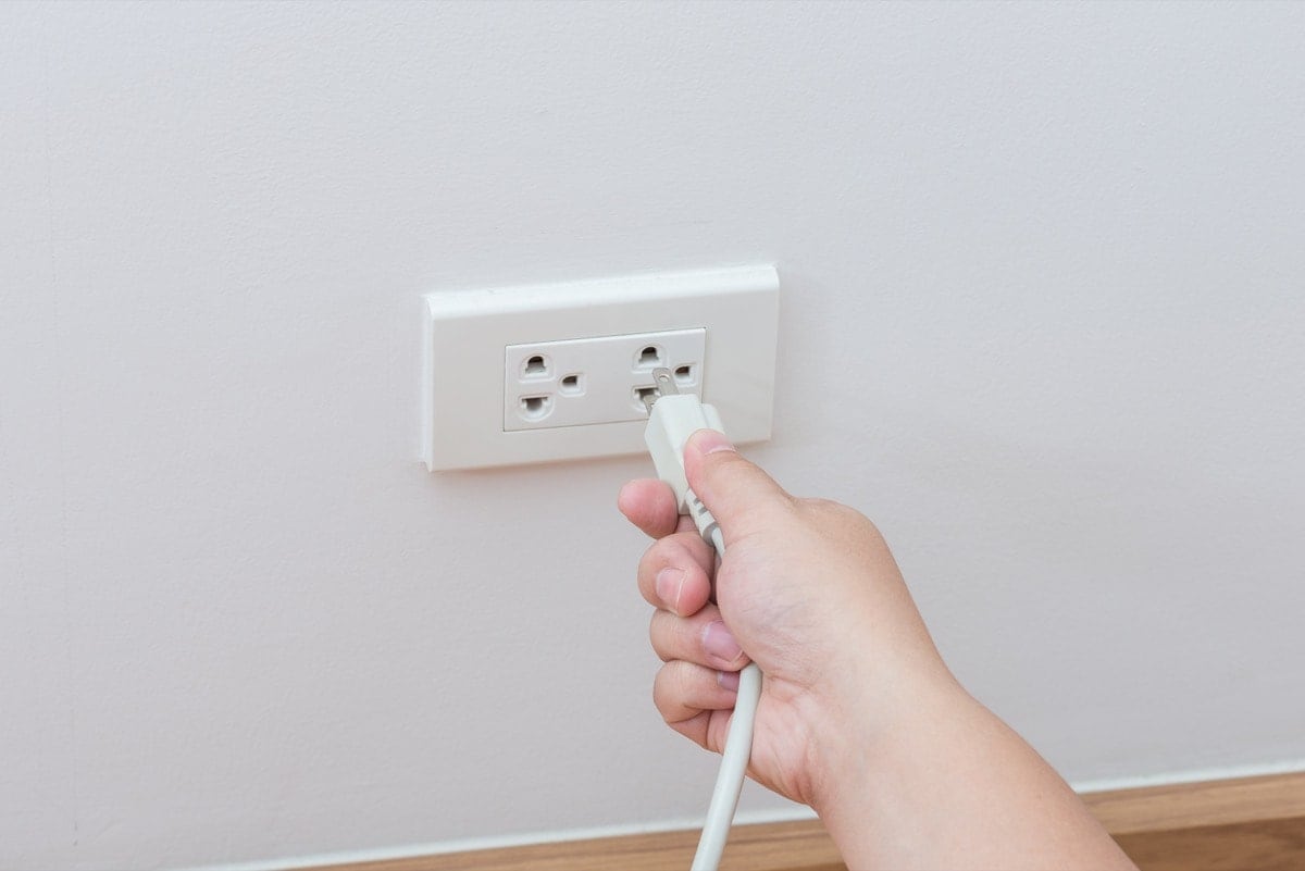 hand inserting cord into electrical outlet